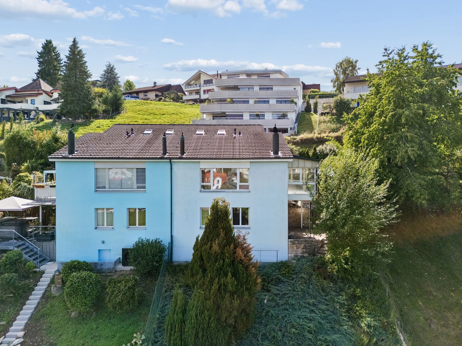 Aussenansicht der hellblau-weissen Hausfassade an einem sonnigen Tag
