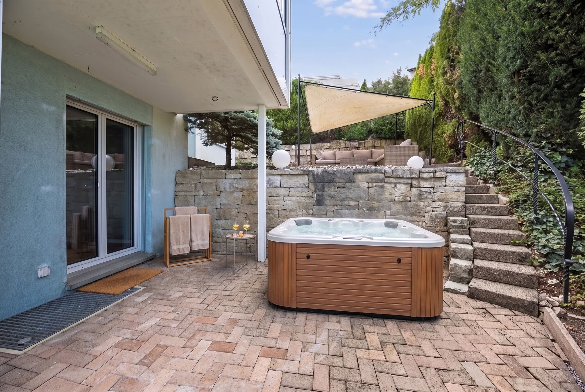 Terrasse mit Sonnensegel und Natursteinmauer