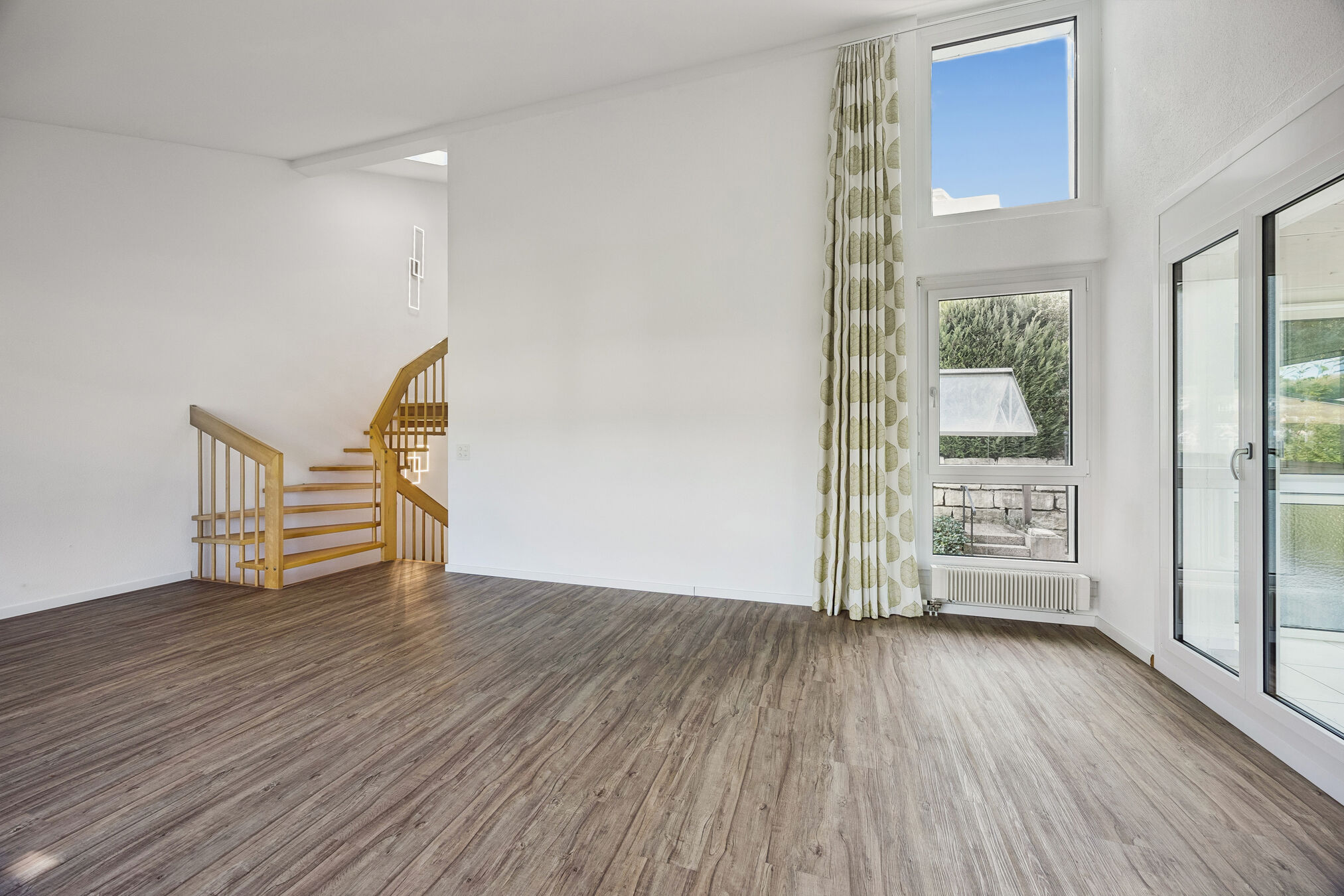 Wohnzimmer mit Galerietreppe und hohen Fenstern